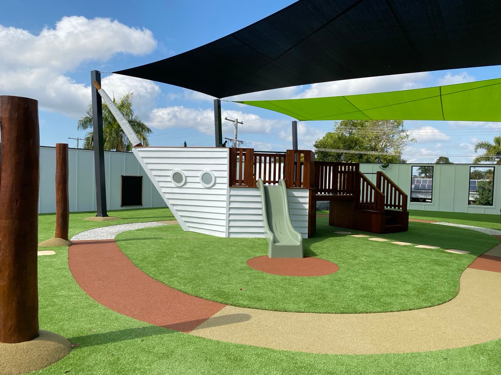 Ship-themed play structure with slide under shade sails